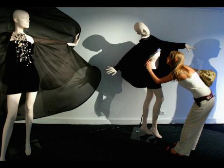 In this July 2006 file photo, a woman looks at a creation by French designer Pierre Cardin as part of his Spring-Summer 2007 fashion collection in Paris. 