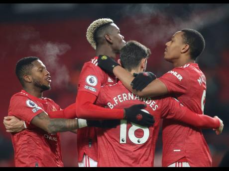 Manchester United’s Bruno Fernandes, (back turned), celebrates with teammates after scoring his sides second goal of the game from the penalty spot during the English Premier League match between Manchester United and Aston Villa at Old Trafford in Manch
