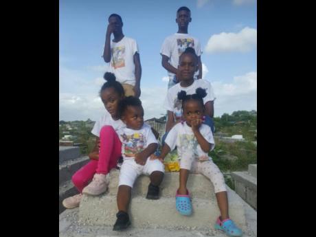 Gerief Phillips’ and Tanisha Reid’s children standing atop their father’s grave.