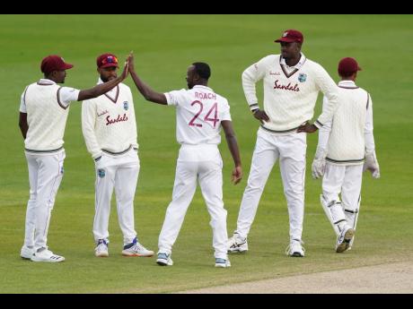 West Indies’ Kemar Roach (centre) celebrates with teammates after the dismissal of England’s Jos Buttler during the fourth day of the second  Test match against England at Old Trafford in Manchester, England, on Sunday, July 19, 2020. 