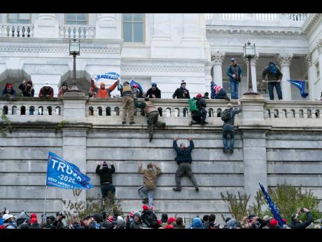 Supporters of President Donald Trump climb the west wall of the US Capitol on January 6, 2021 in Washington.