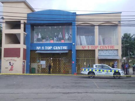 Officers from the Sandy Bay Police Station process the scene of a robbery at the No 1 Top Centre in Hopewell, Hanover, yesterday after gunmen made off with more than $1 million in cash.