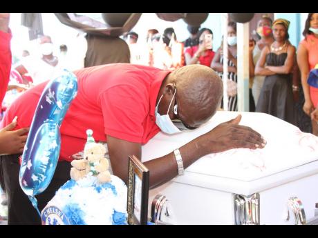 Denham Davidson is overcome with emotions as he hugs the coffin bearing the remains of his grandson, Oshane Banton, during the funeral at the Sedge Pond Basic School in Race Course, Clarendon, yesterday.