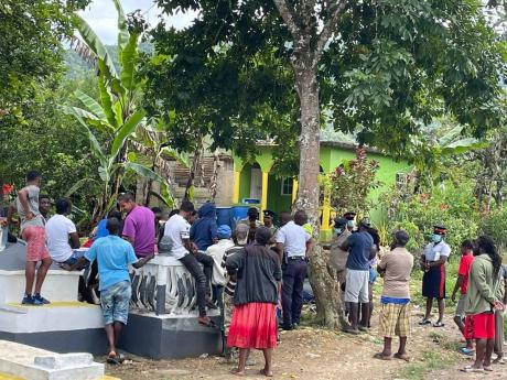 Residents converge outside the Browns’ home in Freeman’s Hall, Trelawny, where a family feud is believed to have triggered a gun attack, which left a four-year-old girl dead and her father hospitalised.