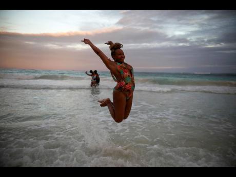An American tourist poses for a photo while jumping in the air in the shallow waters of a beach in Tulum, Quintana Roo state, Mexico, on January 4.