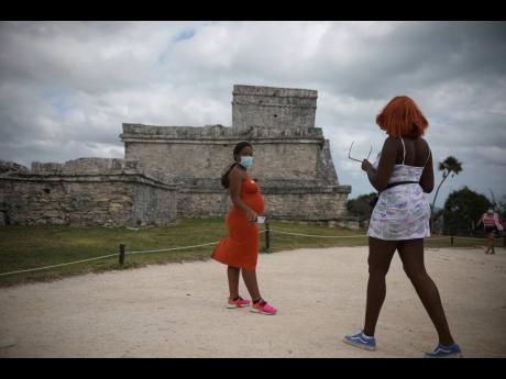 Tourists, required to wear protective face masks amid the new coronavirus pandemic, visit the Mayan ruins of Tulum in Quintana Roo state, Mexico, on January 5. 