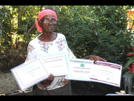 Christine Gayle Ranger, 73 years old, of Corn Piece, Clarendon, displays some of her many certificates received for her craft work and culinary skills. The senior citizen, who volunteers with the 4-H Club, shares her skills with students at Hayes Primary a