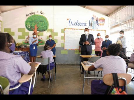 Minister of State in the Ministry of Education, Youth and Information, Robert Morgan (fourth right), addresses students at the Crescent Primary School in St Catherine on Tuesday, following a tour of the institution. At third right is chairman of the school