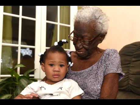 Portmore resident Doris Walker holds her one-year-old great-granddaughter Nahara McFarlane during a small birthday celebration on her 102nd birthday on January 9.
