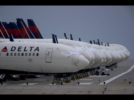 In this May 14, 2020 file photo, several dozen mothballed Delta Air Lines jets are parked on a closed runway at Kansas City International Airport in Missouri. 
