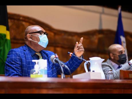 Deputy Mayor of Kingston Councillor Winston Ennis (left), emphasises a point during the monthly meeting of the Kingston and St Andrew Municipal Corporation on January 12, at the Jamaica Conference Centre, downtown Kingston. At right is chief executive offi