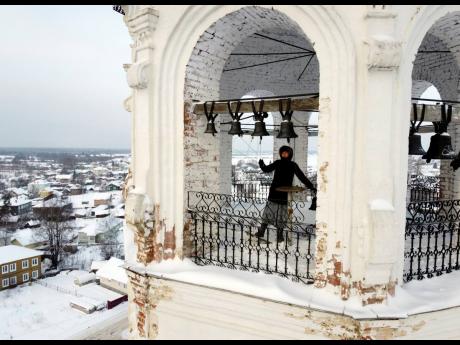A woman rings the bells in the bell tower of the Church of the Entry of the Lord into Jerusalem during the Orthodox Christmas celebration in the city of Totma, about 600 km (370 miles) northeast of Moscow, Russia, Thursday, January 7, 2021. Orthodox Christ