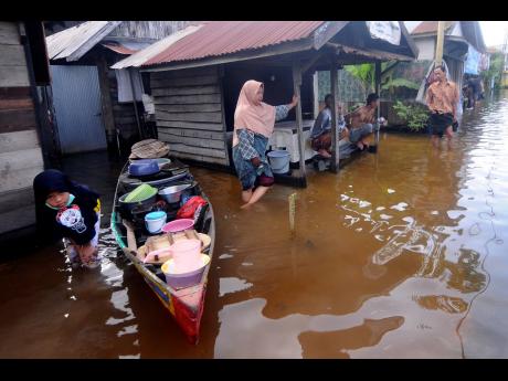 People talk outside their homes at a neighborhood affected by flood in Banjarmasin, South Kalimantan on Borneo Island, Indonesia. Many thousands of people have been evacuated and a number have been killed in recent days in flooding on Borneo island, offici