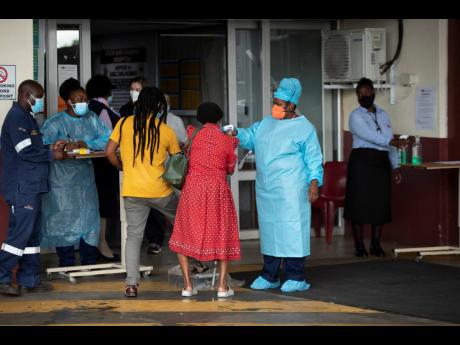 A health worker checks the temperature of an elderly patient at the emergency entrance of the Steve Biko Academic Hospital in Pretoria, South Africa, which is battling an ever-increasing number of COVID-19 patients. 