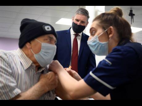 Britain’s Labour leader, Sir Keir Starmer, watches as Melvin Allanson receives the first of two COVID-19 vaccination shots during a visit to the vaccination centre at Robertson House in Stevenage, England.