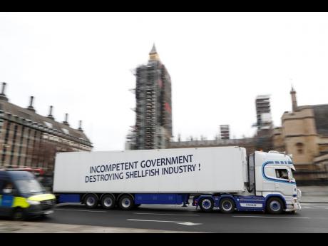 A shellfish export truck with a protest sign written across the trailer, ‘Incompetent Government Destroying Shellfish Industry!’, drives past the Palace of Westminster in London on Monday, January 18, during a demonstration by British shellfish exporte