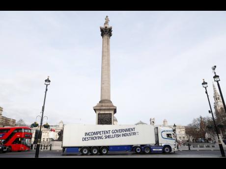 A shellfish export truck with a protest sign written across the trailer, ‘Incompetent Government Destroying Shellfish Industry!’, drives around Trafalgar Square in London on Monday, January 18, during a demonstration by British Shellfish exporters to p