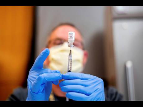 In this January 12 file photo, a pharmacist draws saline while preparing a dose of Pfizer’s COVID-19 vaccine in Sacramento, California.