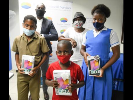 Edwinna Nelson-Thomas (right, background) looks on as granddaughte Sashana Reid (right, foreground), of Seaforth High, and Nelson-Thomas' adopted children, Jaydon Byfield (left) and Shequan Brown, both of Yallahs Primary, display tablets at a presentation 