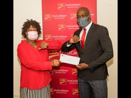 Lancelot Leslie (right), chief financial officer, CIBC FirstCaribbean International Bank, presents a cheque to Judy Mowatt for the benefit of her Judy Mowatt Outreach Ministries’ Fuel For The Brain Breakfast Programme at Bath Primary and Junior High Scho