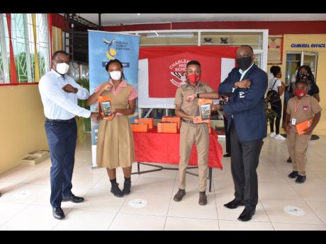 Jamaica Energy Partners (JEP) Group President & CEO Wayne McKenzie and Chief Technical Officer Cecil Gordon present tablets to Abigail Smith (left) and Tajeir Murray. JEP presented the Charlemont High School’s administration with 25 tablets for students 