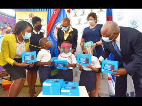 Minister of Education, Youth and Information Fayval Williams (third left, background) participates in the handover of tablets at the Union Gardens Infant School, St Andrew, on Tuesday. Others (from left) are: Principal of the school Grace-Ann Moss-Solomon;