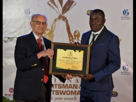 National senior men's football team head coach Theodore Whitmore (right) receives his Certificate of Merit from Selection Committee Chairman Mike Fennell at the RJRGLEANER Sports Foundation National Awards on Friday.