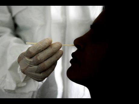 A doctor takes a nasal swab sample to test for COVID-19 at the Cocodrilos Sports Park in Caracas, Venezuela.