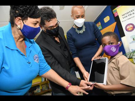 Douglas Augustine Ekele Mukwelle (right), shows his tablet to Reece King (second left), of RMP and Associates Limited, Fayval Williams (right) Minister of Education, Youth and Information and Greta Bogues, CEO of The Private Sector Organisation of Jamaica 
