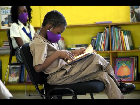 Douglas Augustine Ekele Mukwelle, reads a book while waiting on his tablet, donated by RMP and Associates Limited at John Mills Primary and Infant School on January 22.