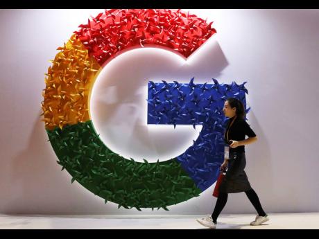 In this November 5, 2018 photo, a woman walks past the logo for Google at the China International Import Expo in Shanghai. Google says it’s making progress on plans to revamp Chrome user tracking technology.