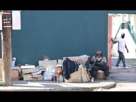 A homeless man sitting outside the gates of Palace Amusement’s Carib 5 cinema in Cross Roads, St Andrew, with all his worldy possessions yesterday. At least six homeless men were attcked on the streets of the Corporate Area on Sunday night.