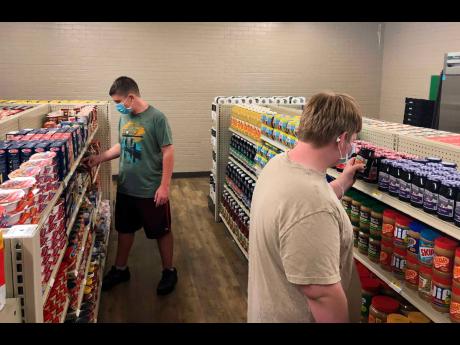Hunter Weertman (left), a 16-year-old student at Linda Tutt High School, stocks shelves and takes inventory while working as a manager of the student-led free grocery store in Sanger, Texas.