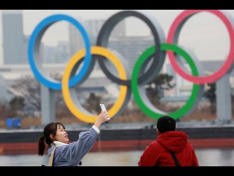 A woman poses for a selfie in front of Olympic rings at Odaiba waterfront in Tokyo, Tuesday, January 26, 2021. The postponed Tokyo Games are scheduled to open on July 23. 
