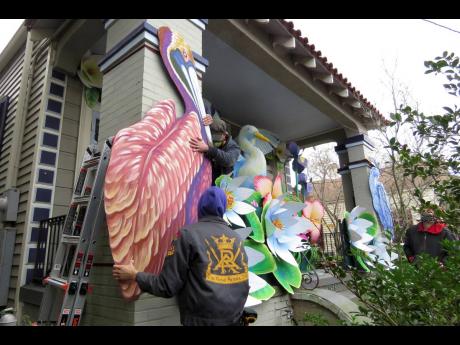 Parade float workers Travis Keene (left) and Joey Mercer position a pelican while fellow crew member Chelsea Kamm (right) looks on, as the two decorate a house in New Orleans.