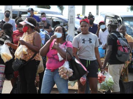 Vendors and other persons in Mandeville, Manchester, look on as a health ministry team (not pictured) marches through the town emphasising the need for wearing of masks to guard against the coronavirus. Health Minister Dr Christopher Tufton expressed disap