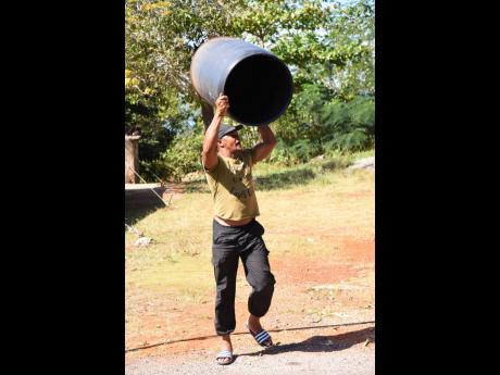 Steve Harvey lifts an empty drum while relating the plight of residents in Planters Hall, St Catherine, where their pipes remain dry and they believe they have been left to pray for rains.