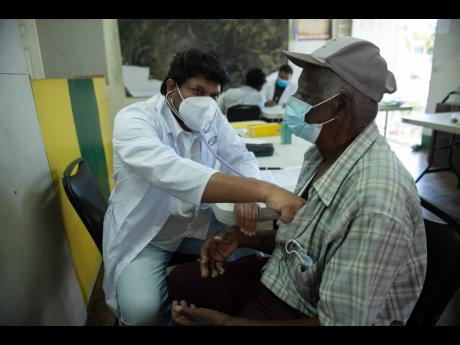 Dr Anil Kandikatla examines 89-year-old Julius Roy at the Pan-Jamaica India Day medical camp held at the Constant Spring Library on Sunday. Residents of Cassava Piece benefited from free health checks and medication courtesy of the Indian High Commission.