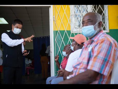 Indian High Commissioner Masakui Rungsung gestures to prospective patients awaiting their turn to be seen by doctors at the Pan-Jamaica India Day free medical camp held at Constant Spring Library on Sunday.