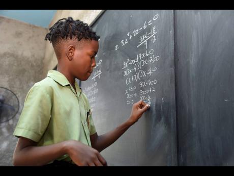 Eleven-year-old Dreshaun Napier demonstrates his knowledge by tackling a Caribbean Secondary Education Certificate-level algebra problem at Kemet-Maasai Academy in Portmore, St Catherine, yesterday. Dreshaun received a distinction in City & Guilds mathemat