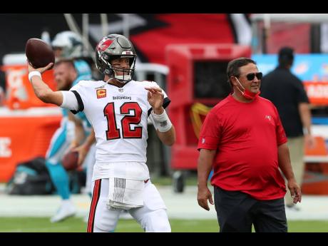 Tampa Bay Buccaneers quarterback Tom Brady (left) throws a pass as quarterback’s coach Clyde Christensen looks on before an NFL football game against the Carolina Panthers on Sunday, September 20, 2020, in Tampa, Florida.