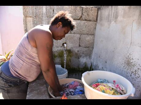 Spanish Town resident Terry-Ann Miler doing her weekly laundry at home on Tuesday. The single mother of three said that care work has multiplied in the home since the onset of COVID-19 even as her main income stream has been cut.