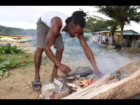 Fisherman Kevin Ricketts roasts fish and crab on woodfire at Pagee Beach in St Mary on Wednesday. He explained that with a small catch for the day, he resorted to just roasting what he caught.