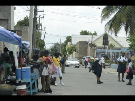File 
In this 2017 photo, students stop by a vendor to purchase snacks, sweet treats and juices on their way home from school in Southside, Kingston.