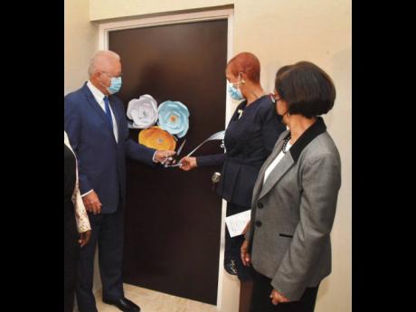 Justice Minister Delroy Chuck (left) is assisted by Minister of Education, Youth and Information and Member of Parliament for St Andrew Eastern, Fayval Williams, in cutting the ribbon to reopen the August Town Restorative Justice Centre at its new location