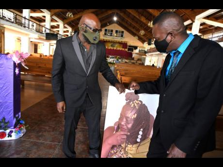 Richie Stephens (left), and Little Lenny look at a portrait of Yvonne Sterling placed at the entrance of the Portmore Seventh-day Adventist Church. Sterling received assistance from industry players prior to her death, including Richie Stephens and Little 