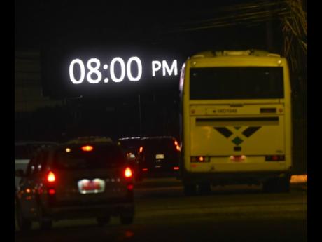 A Jamaica Urban Transit Company bus drives towards an automated billboard in the vicinity of the Portmore Mall in St Catherine on Tuesday night. Prime Minister Andrew Holness announced a tighter two-week national curfew set to begin at 8 p.m. today.