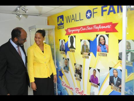 Earl Jarrett (left), deputy chairman and chief executive officer of The Jamaica National Group, congratulates Karen Oliver on her achievement.