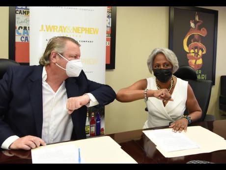 Chairman of Crime Stop Sandra Glasgow elbow bumps Jean-Philippe Beyer, managing director of J. Wray and Nephew Ltd, on Wednesday during the signing of an agreement for the donation of US$10,000 annually. 