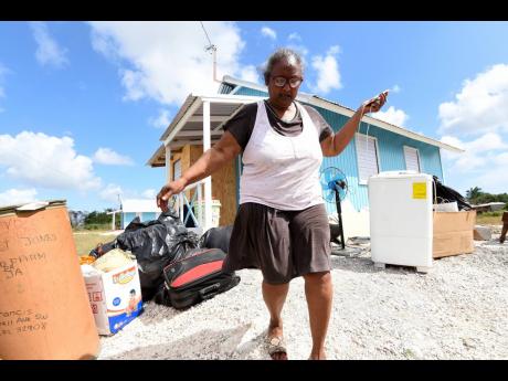 Margaret Jones,55, walks past her belongings at an unfinished house in McCooks Pen, St Catherine, on Saturday. She said the house was unfit for occupancy and complained about plumbing and other defects. 